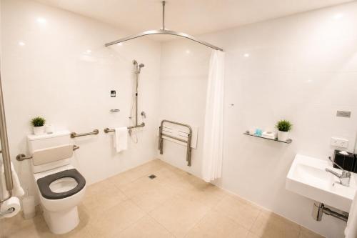 a white bathroom with a toilet and a sink at Woodroffe Hotel in Gold Coast