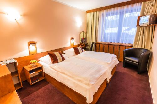 a hotel room with a large bed and a chair at Hotel Sachticka in Banská Bystrica