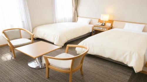 a hotel room with two beds and a chair at Center Hotel Mihara in Mihara