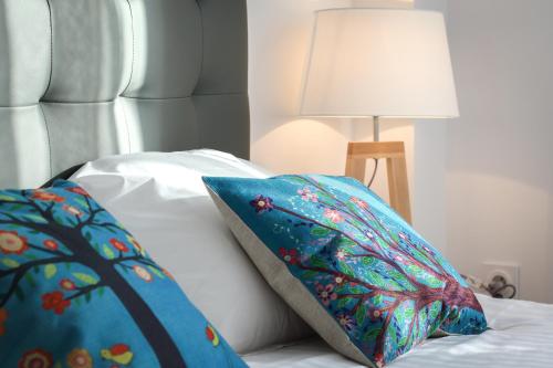 a white bed with a blue pillow and a lamp at Résidence les Cèdres in Strasbourg