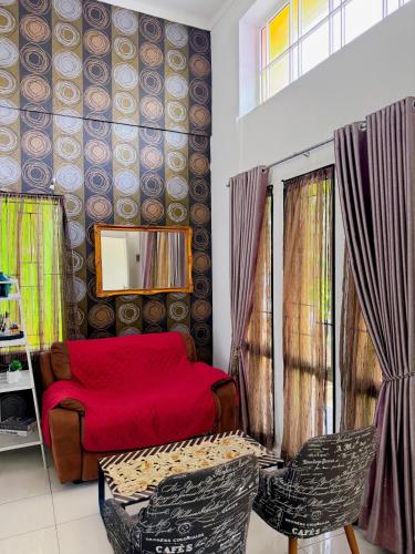 a living room with a red bed and two chairs at Arcovella House in Cikarang