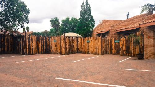 a wooden fence in front of a parking lot at Aark Guest Lodge in Vanderbijlpark