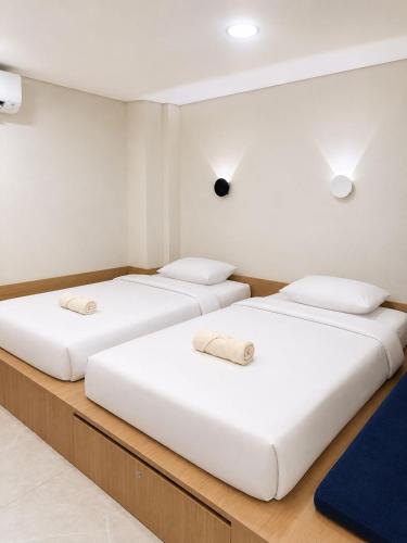three beds in a room with white walls at Una Hotel in Mantaak