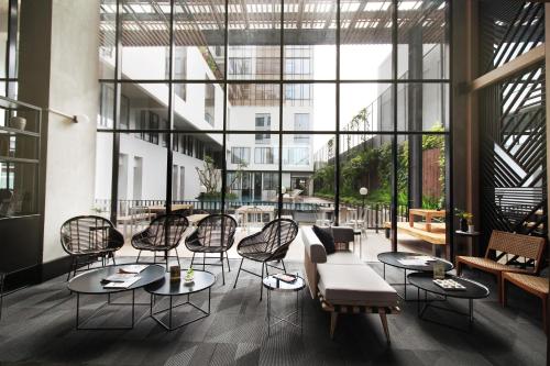 a lobby with chairs and tables and windows at GAIA Cosmo Hotel in Yogyakarta