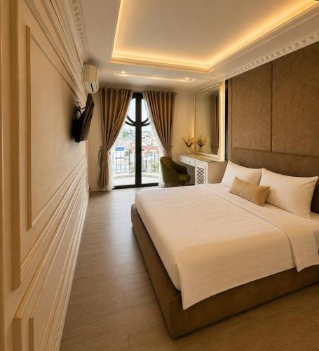 a bedroom with a large bed and a window at D'Élite Boutique Hotel Dĩ An in Dĩ An
