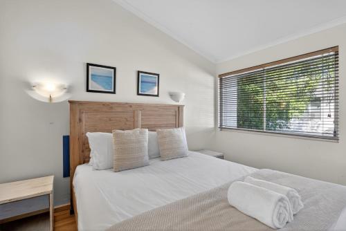 a white bedroom with a bed and a window at Noosa Parade Holiday Inn in Noosa Heads