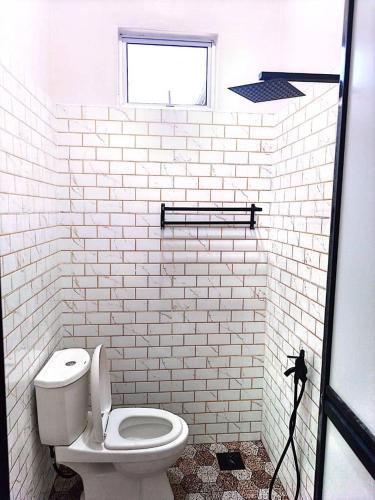 a white bathroom with a toilet and a window at Adeeb Homestay in Tumpat