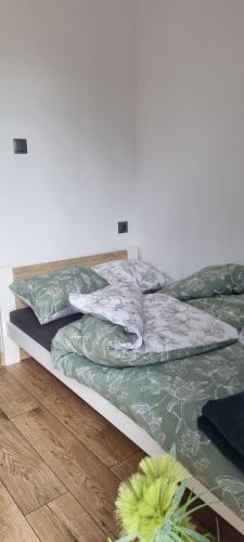a bed with green and white sheets and a wooden floor at Nestor Baron in Borkowo