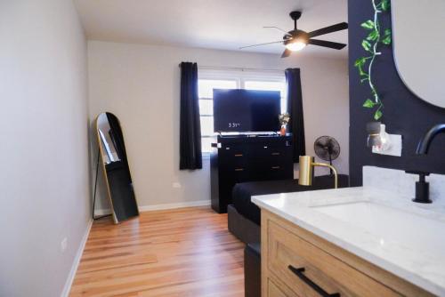 a bathroom with a sink and a television in a room at Jacuzzi Cul de Sac Home in Country Club Hills