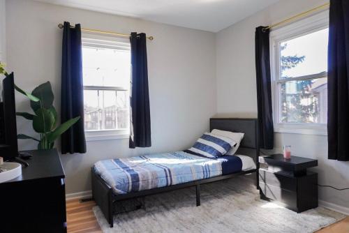 a bedroom with a bed and two windows at Jacuzzi Cul de Sac Home in Country Club Hills