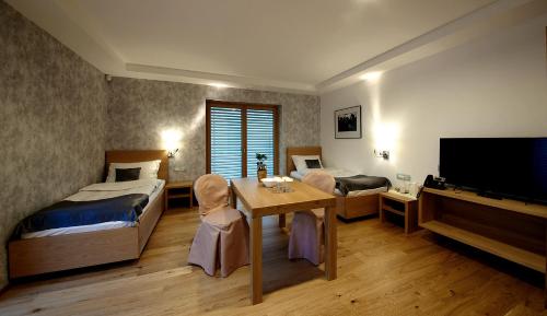 a bedroom with two beds and a table and a television at Pan Prenočišča in Ptuj