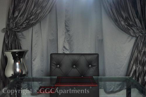 a glass table and a chair in a room with curtains at GGC Luxury Serviced Apartment - Platinum in Lagos