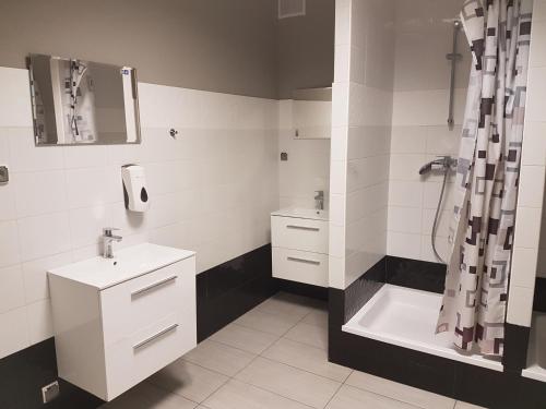 a white bathroom with a sink and a shower at Duszka Hostel in Warsaw