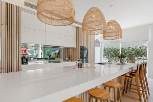 a kitchen with a white counter and wooden stools at Key Court 17 in Noosa Heads