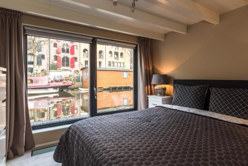 a bedroom with a bed and a large window at Houseboat-Apartment Sumatra in Amsterdam