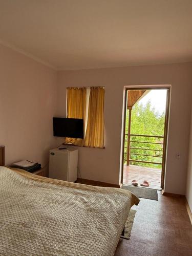 a bedroom with a bed and a sliding glass door at Green House in Cholpon-Ata