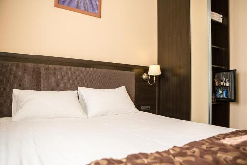 a bed with white pillows in a hotel room at Churchill-Inn in Vinnytsya