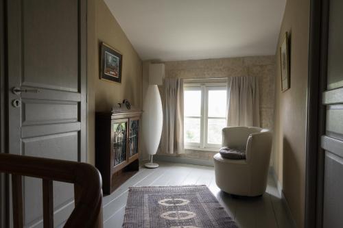 a living room with a chair and a window at La Tillaie SPA et Sauna in Pont-lʼAbbé-dʼArnoult