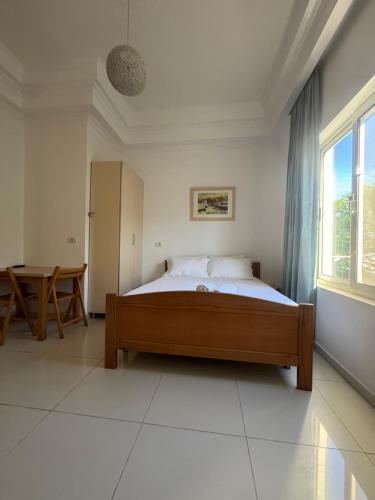 a bedroom with a bed and a table and a window at KuneVain Guest House in Lezhë