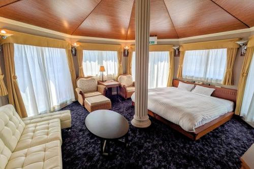 a bedroom with a bed and a couch and a chair at Hotel Castle Inn Tsu in Tsu