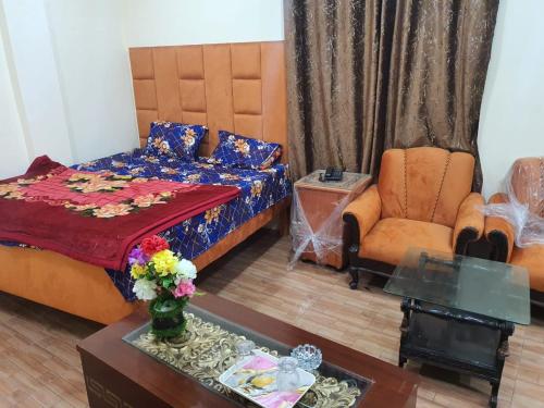 a bedroom with a bed and a chair and a table at New aalbayan hotel in Lahore