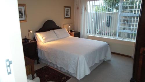 a bedroom with a white bed and a window at At 29 Columba in Groot Brak Rivier