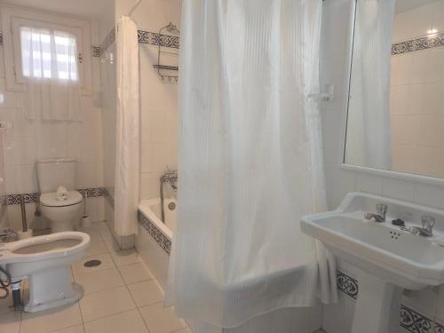 a white bathroom with a toilet and a sink at Calma Bungalow 54b en Urbanización La Roca in Torremolinos