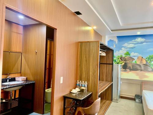 a bathroom with a sink and a room with a painting at MELANTA HOTEL FLC SẦM SƠN in Sầm Sơn