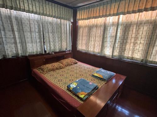 ein kleines Schlafzimmer mit einem Bett und zwei Fenstern in der Unterkunft SP Home at Maesot in Mae Sot