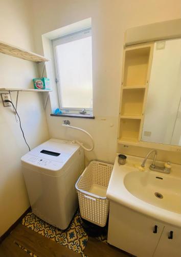 a bathroom with a toilet and a sink and a window at Guest House Rakufu in Anan