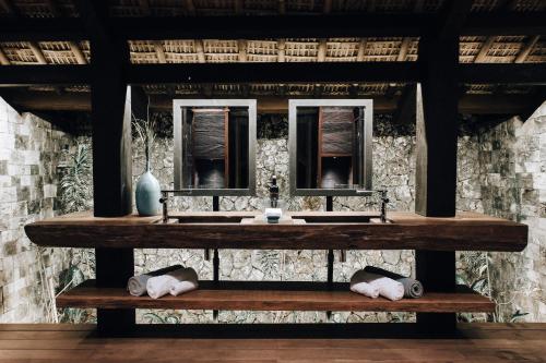 a bathroom with two sinks and two mirrors at Suarga Padang Padang in Uluwatu