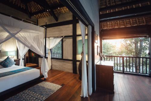 a bedroom with a canopy bed and a balcony at Suarga Padang Padang in Uluwatu