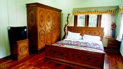 a bedroom with a wooden bed and a television at Devega Homestay in Yogyakarta