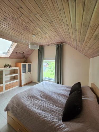 a bedroom with a large bed with a wooden ceiling at Cosy Hideaway Guest House in Dovilai
