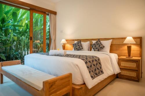 a bedroom with a large bed and a window at River Temple Villa in Ubud
