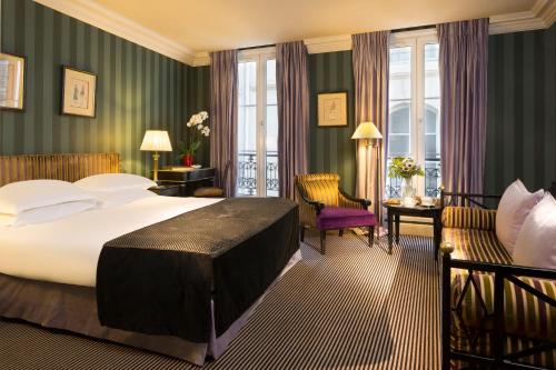 パリにあるヴィラ デストレの大きなベッドと椅子が備わるホテルルームです。