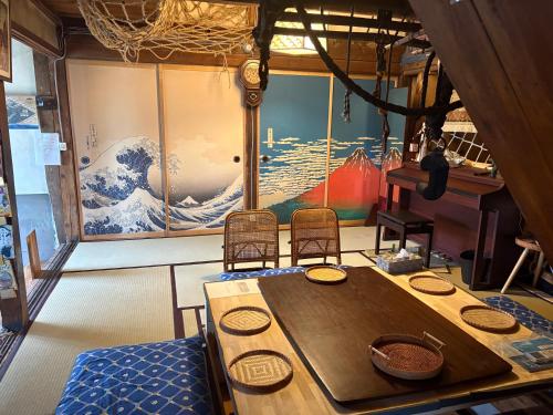 a room with a table and chairs and a large painting at 一棟貸しの宿 餓鬼大将と別館トキワ荘 in Omachi
