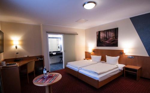 a hotel room with a bed and a table at Hotel-Restaurant Fröhlich in Kaiserslautern