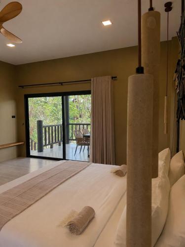 a bedroom with a large bed and a balcony at Secret Cottages Chaweng Noi in Koh Samui
