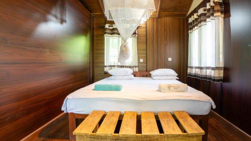 a small bedroom with a bed and a bench at The Thick Forest in Sigiriya