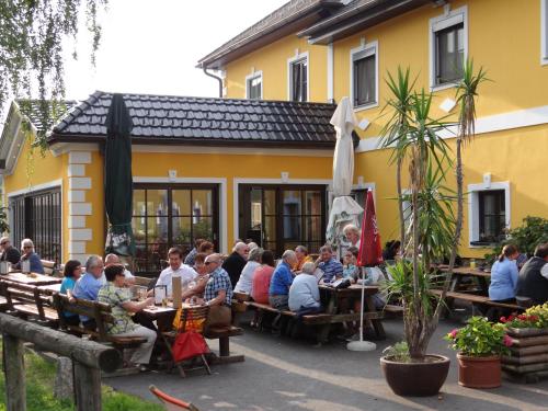 a group of people sitting at tables outside of a building at Perbersdorfer Heuriger in Neuhofen an der Ybbs