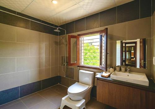 a bathroom with a toilet and a sink and a window at Miu Homestay Hue in Thôn Lại Thê