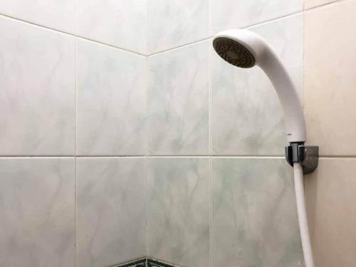 a shower head on a wall in a bathroom at SAS Guest House Mitra RedDoorz At Darmo Park 2 Surabaya in Surabaya