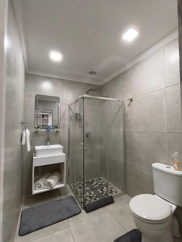 a bathroom with a shower and a toilet and a sink at Wag-n-Bietjie in Centurion