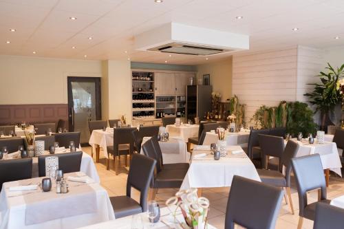 a dining room with white tables and chairs at Logis Hotel Restaurant La Croix Verte in Neau