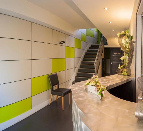 a lobby with a chair and a staircase at Logis Hotel Restaurant La Croix Verte in Neau