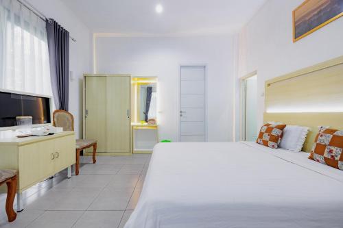 a bedroom with a large white bed and a television at RedDoorz at Batutulis Bogor Villa Papatong by M in Bogor