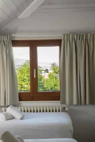 a bedroom with two beds and a window at Auberge de Confignon in Geneva
