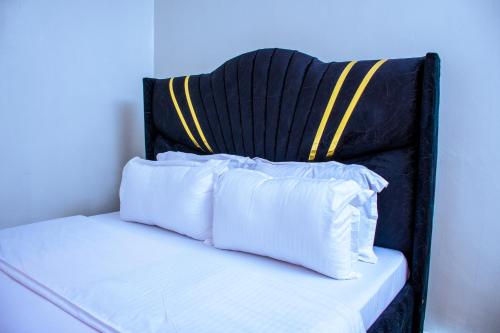a bed with white pillows and a black and yellow headboard at JULIAH NASERIAN BnBS in Narok