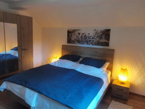 ein Schlafzimmer mit einem Bett mit blauer Bettwäsche und zwei Lampen in der Unterkunft Grey House in Laufen